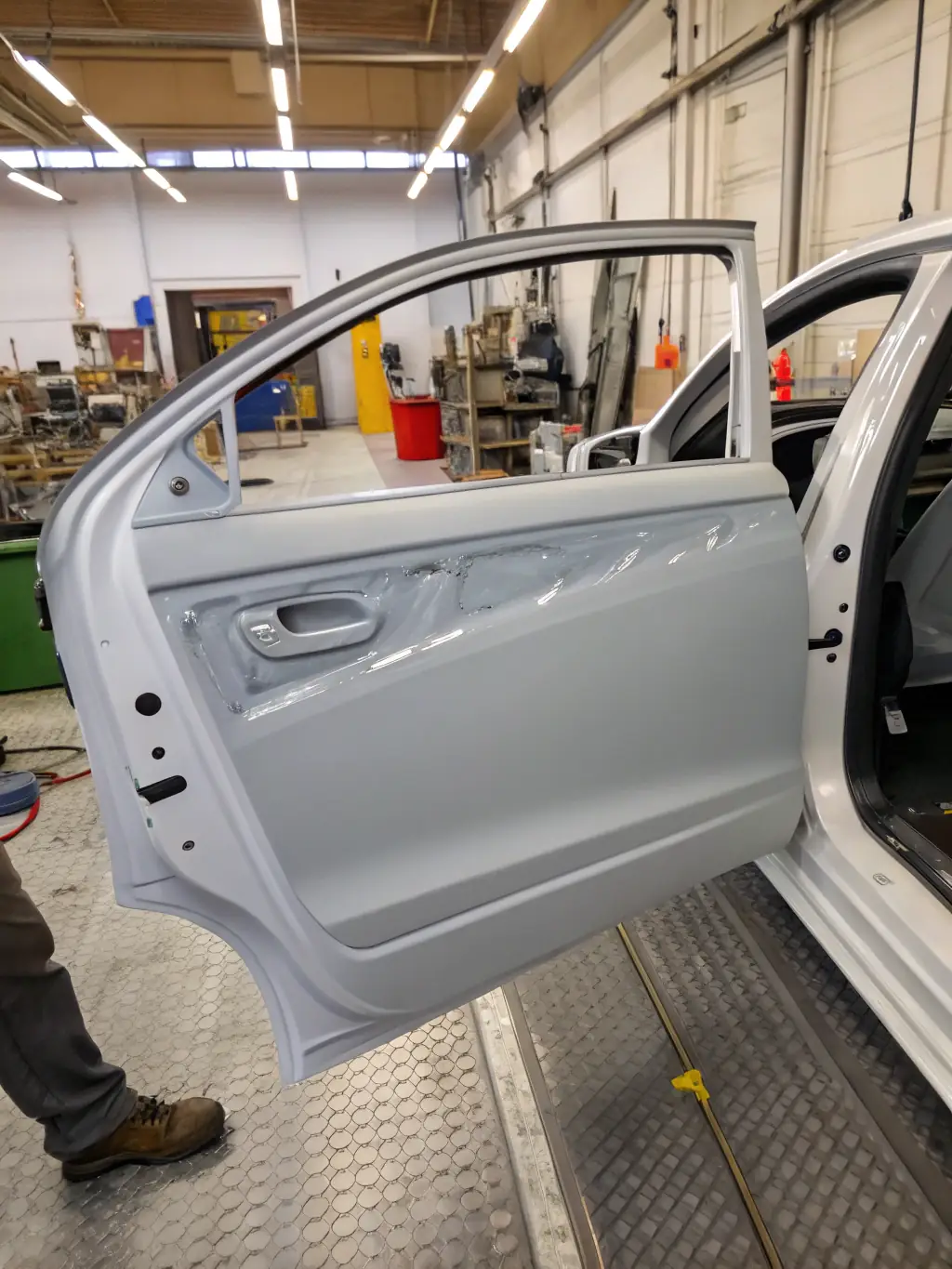 A close-up shot of a ProAutoBody technician expertly applying a fresh coat of paint to a car panel in a clean, well-lit booth, showcasing the precision and quality of their auto body painting service.